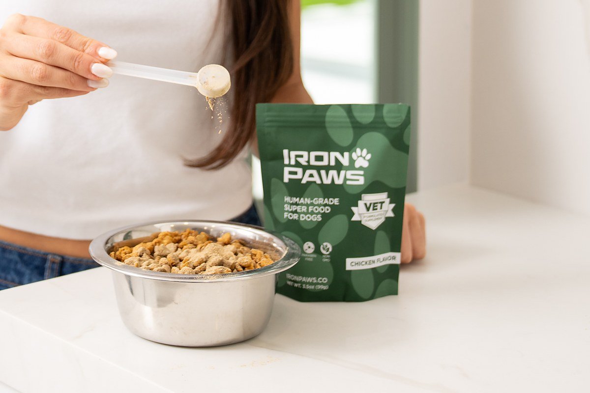 Iron Paws Daily Superfood beside a bowl of dog food